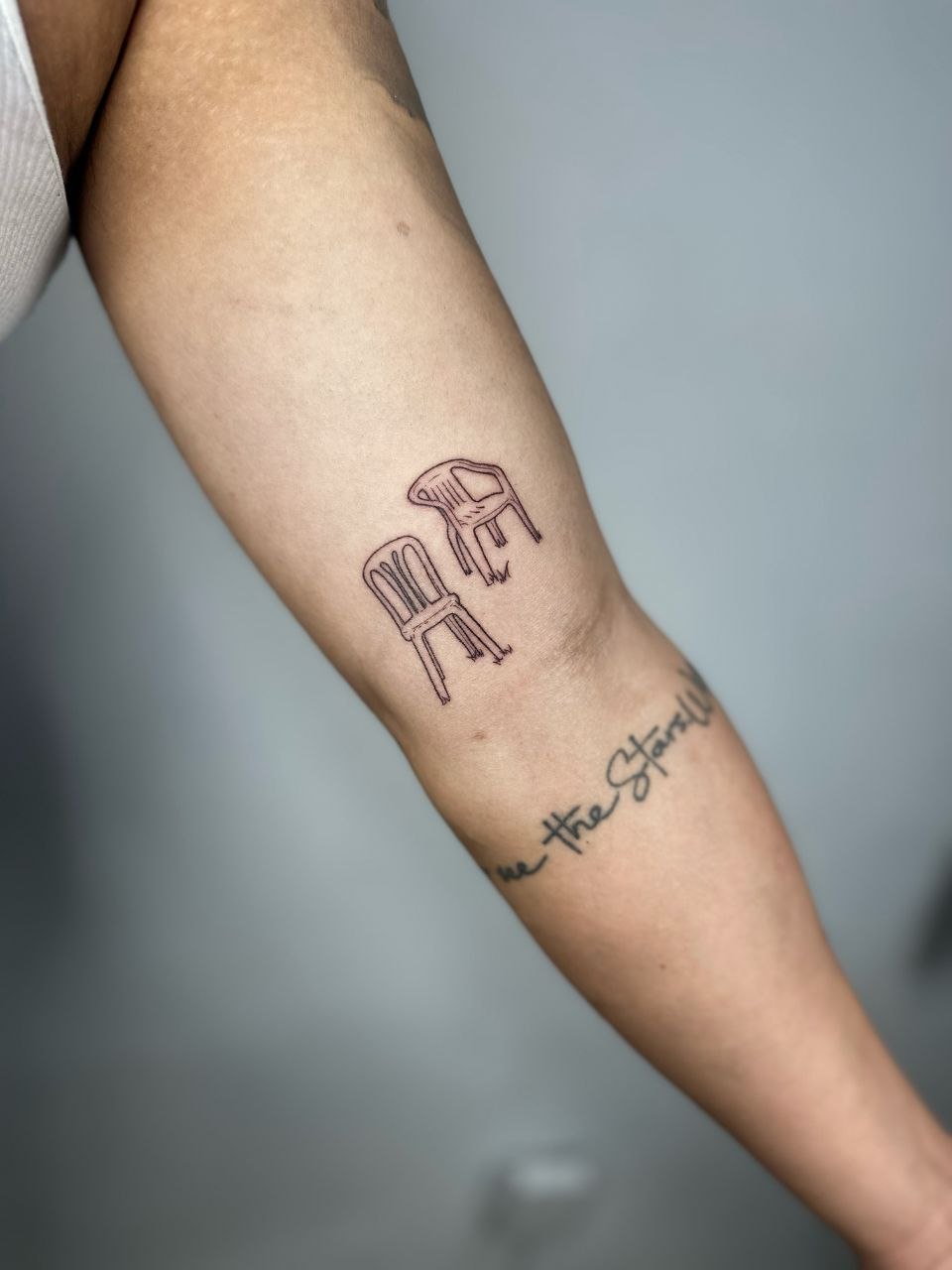 Tatuaje minimalista de dos sillas para recuerdo de viaje